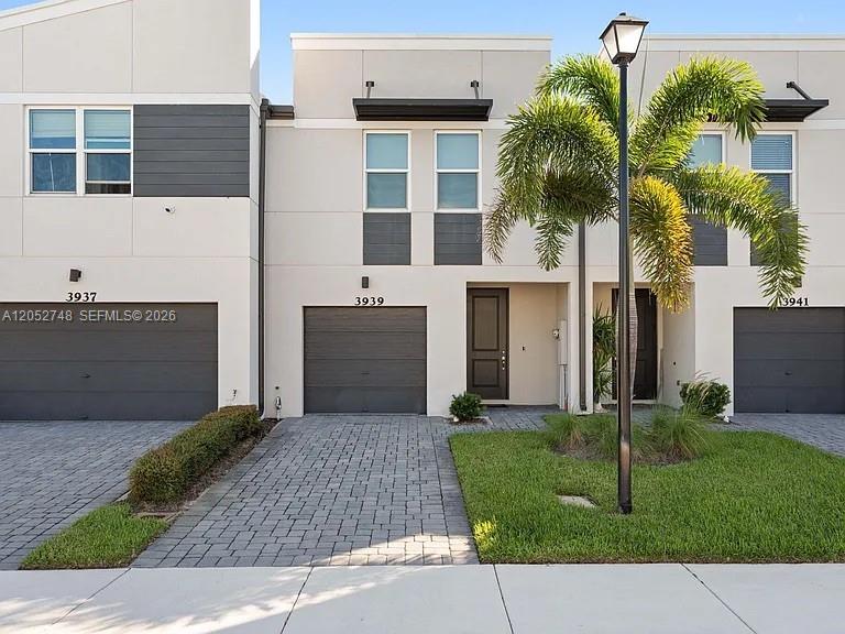 The exterior view shows three modern townhouses with gray garage doors and paved driveways — 3939 SE Mentmore Ln # 3939, Stuart FL 34997, STUART, FL