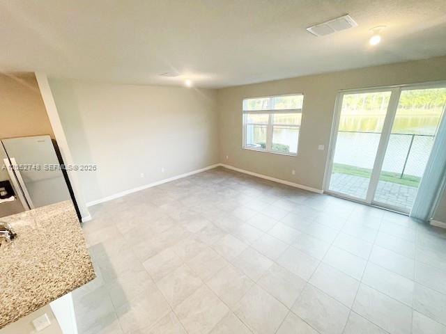 An open-concept living area features light-colored tile flooring, neutral walls, and sliding glass patio doors — 3939 SE Mentmore Ln # 3939, Stuart FL 34997, STUART, FL