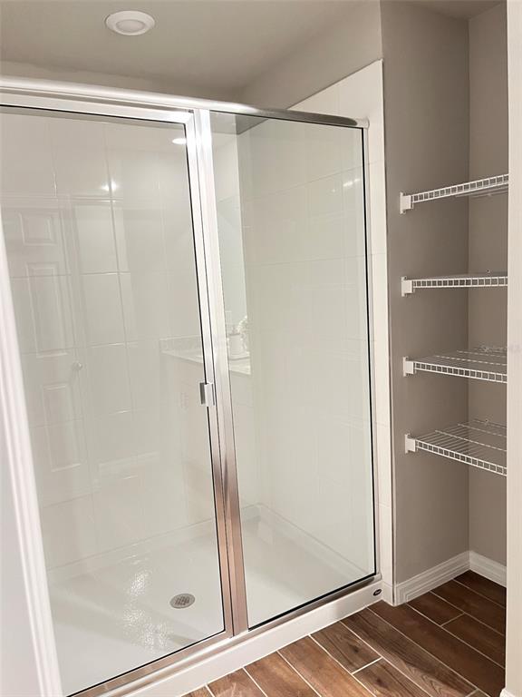 A walk-in shower with a glass door sits next to open wire shelving — 437 LEGACY LOOP, DAVENPORT, FL