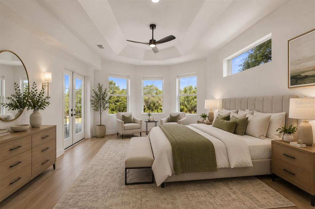 A bright bedroom features a tray ceiling, light wood floors, and a neutral color palette — 17545 GLENDA DRIVE, SPRING HILL, FL