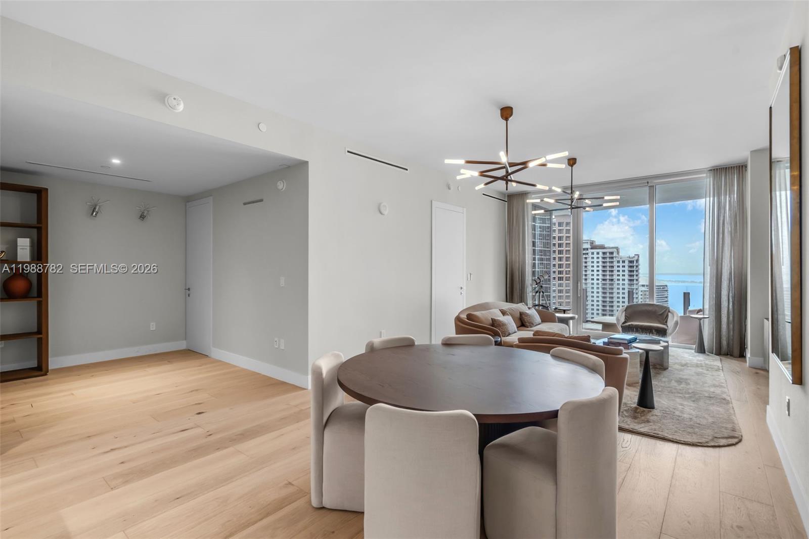 A dining area with a round table and a living room with floor-to-ceiling windows — 300 Biscayne Boulevard Way # 2605W, Miami FL 33131, MIAMI, FL