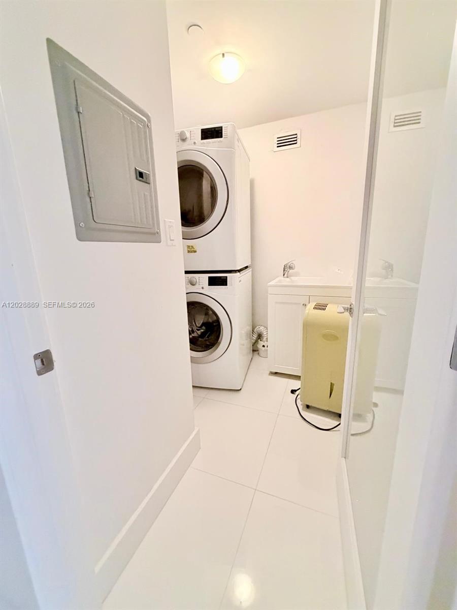 This laundry room features a stacked washer and dryer, a utility sink, and white tile — 100 Lincoln Rd # 1504, Miami Beach FL 33139, MIAMI BEACH, FL