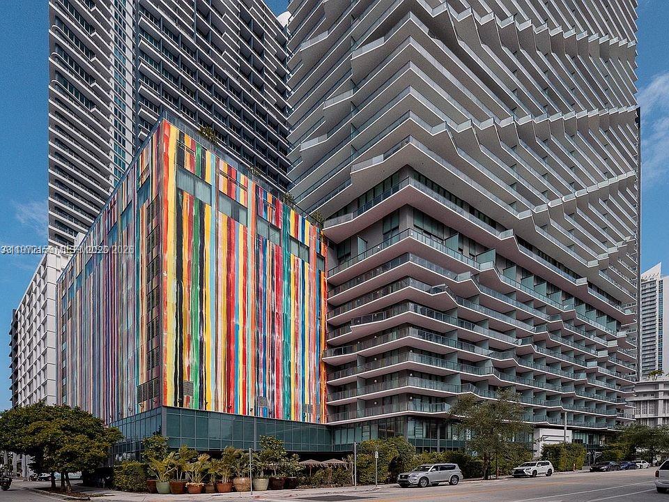 A colorful, vertically striped building stands next to a modern high-rise with zigzag balconies — 1300 S Miami Ave # 2006, Miami FL 33130, MIAMI, FL