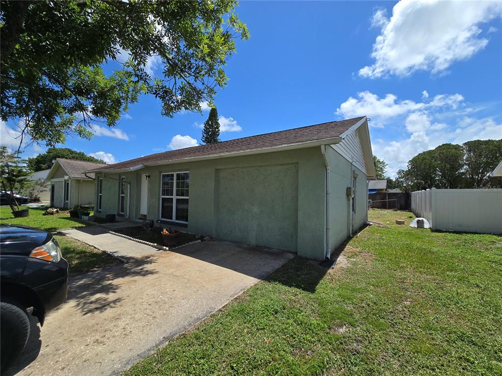 A single-story house with a green stucco exterior, a concrete driveway, and a white fence — 3406 MURROW STREET, NEW PORT RICHEY, FL