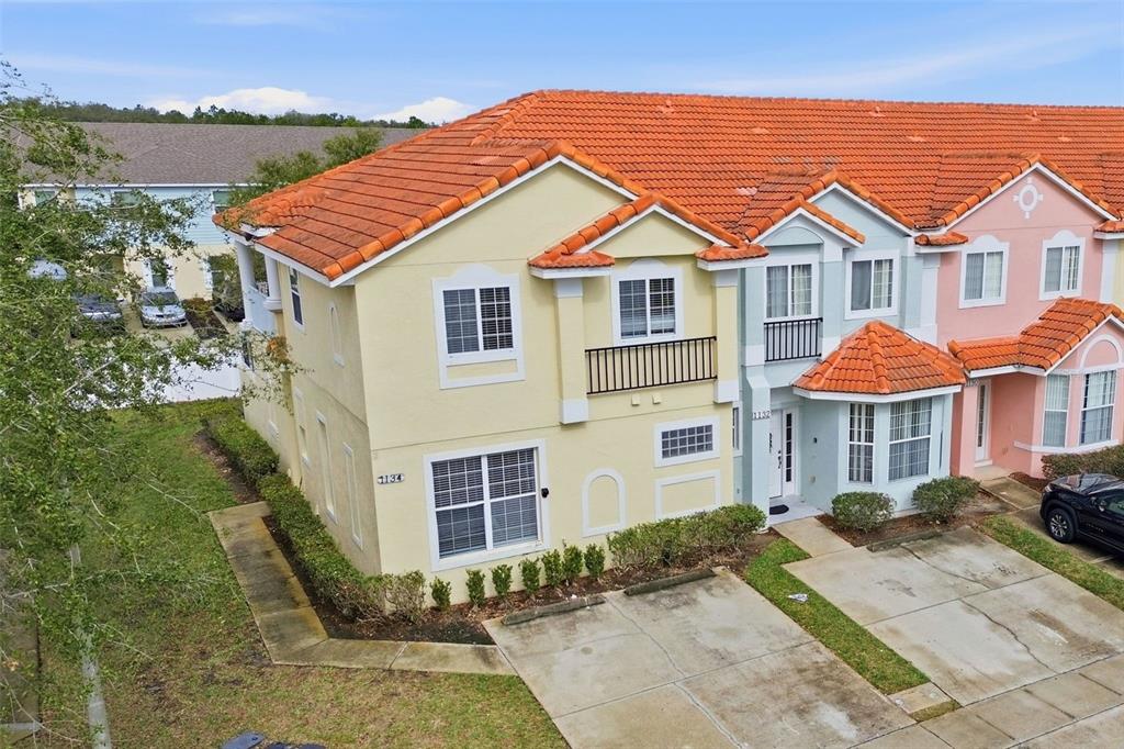 An exterior view of a multi-story townhouse complex with orange tile roofs and driveways — 1134 S BEACH CIRCLE, KISSIMMEE, FL