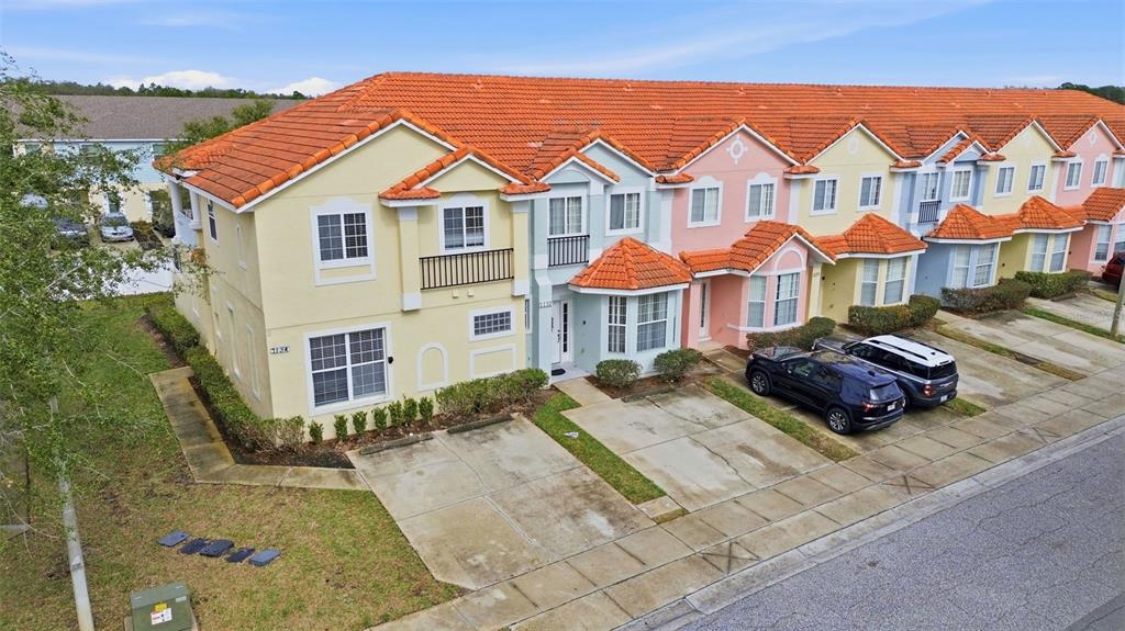 An aerial view of a multi-unit townhouse complex with orange tile roofs and pastel facades — 1134 S BEACH CIRCLE, KISSIMMEE, FL