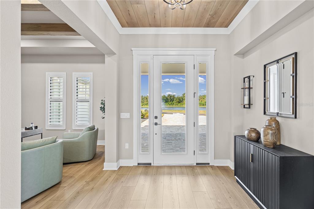 An entryway features light wood floors, a coffered ceiling, and a glass-paneled front door — 728 ESTATES BOULEVARD, TARPON SPRINGS, FL