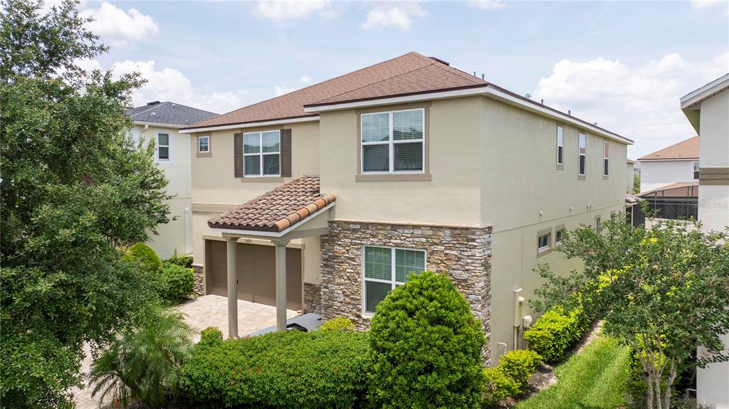 A two-story house with a tan stucco exterior, stone facade, and a tiled garage entrance — 1505 NASSAU POINT TRAIL, KISSIMMEE, FL