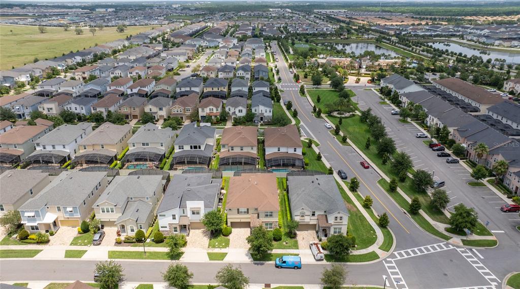 An aerial view shows a suburban neighborhood with houses, a parking lot, and a pond — 1505 NASSAU POINT TRAIL, KISSIMMEE, FL