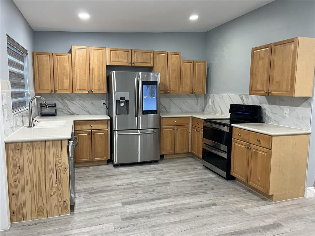 A kitchen features light wood cabinets, stainless steel appliances, and white marble-patterned backsplashes — 1746 8TH STREET, SARASOTA, FL