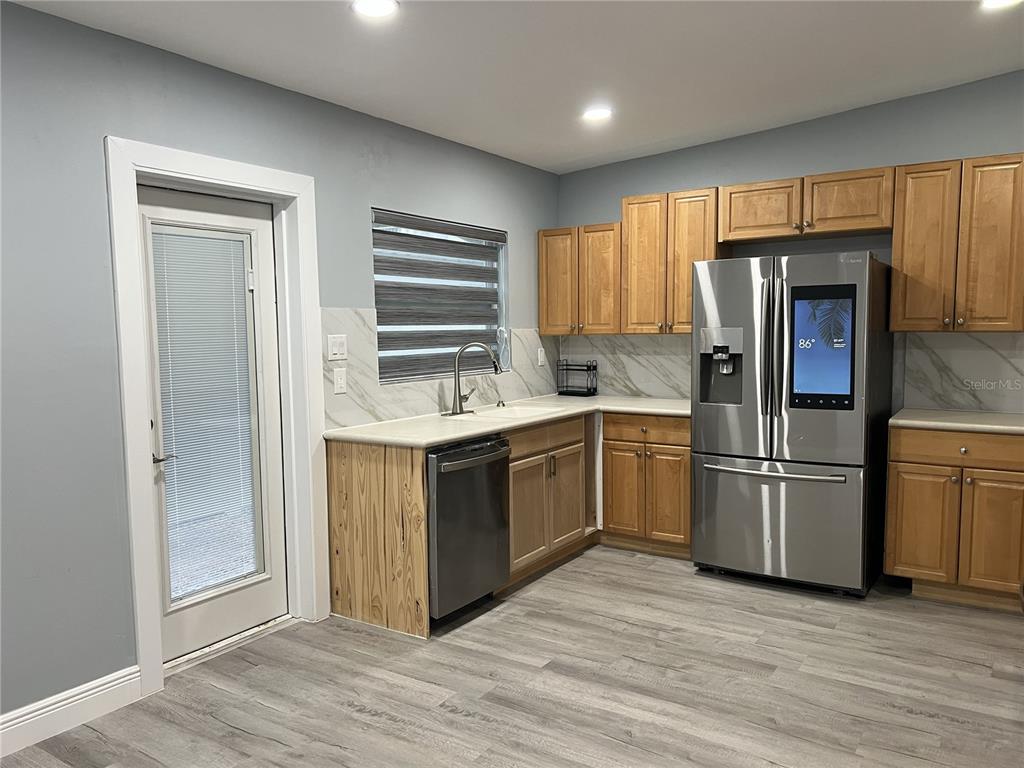 A kitchen features light wood cabinets, stainless steel appliances, and a marble-patterned backsplash — 1746 8TH STREET, SARASOTA, FL