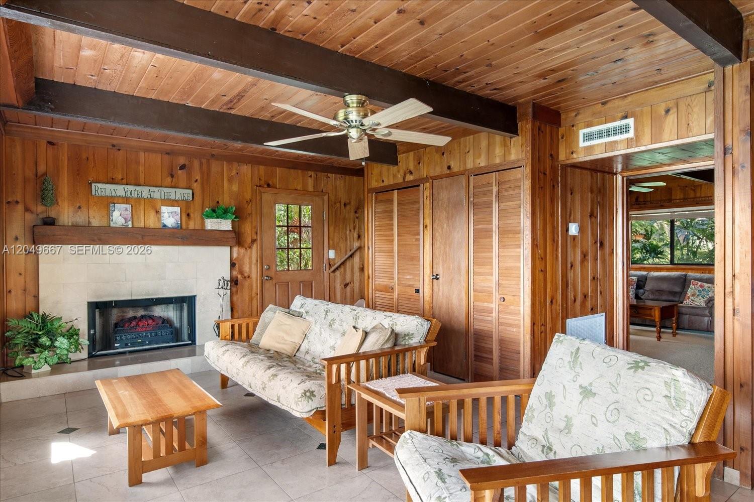 A living room features wood-paneled walls, a fireplace, a ceiling fan, and tile flooring — 106 Wilmac Dr, Lake Placid FL 33852, LAKE PLACID, FL