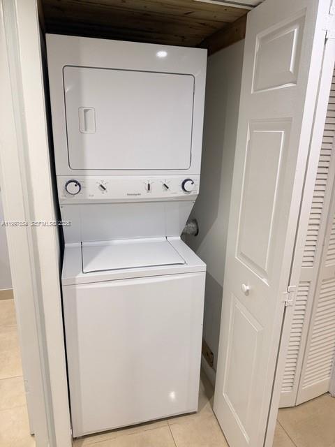 A white stacked washer and dryer unit sits inside a closet with louvered doors — 100 Lakeview Dr # 115, Weston FL 33326, WESTON, FL