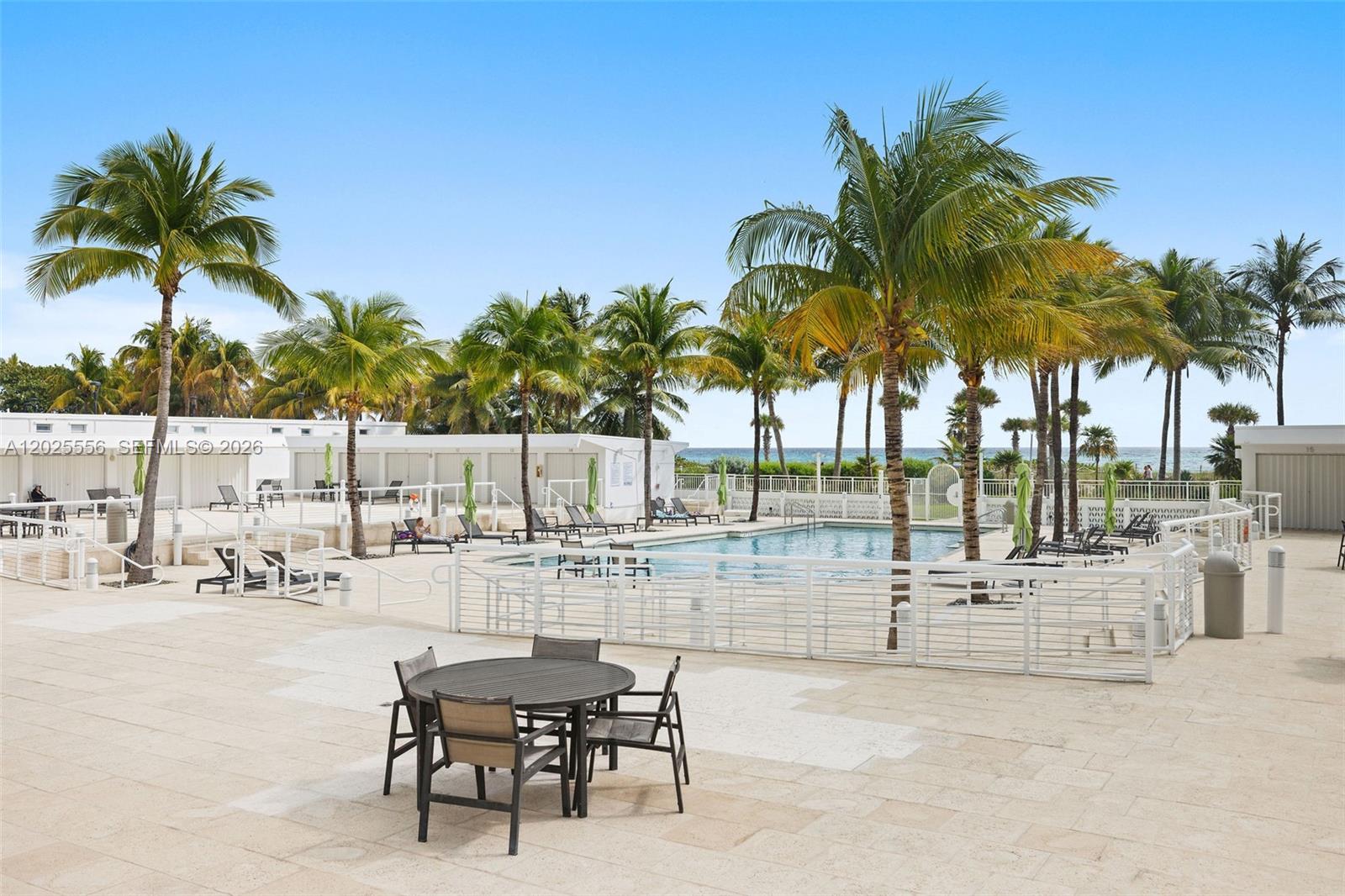 A swimming pool area features palm trees, lounge chairs, and a patio dining set — 4925 Collins Ave # 1A, Miami Beach FL 33140, MIAMI BEACH, FL