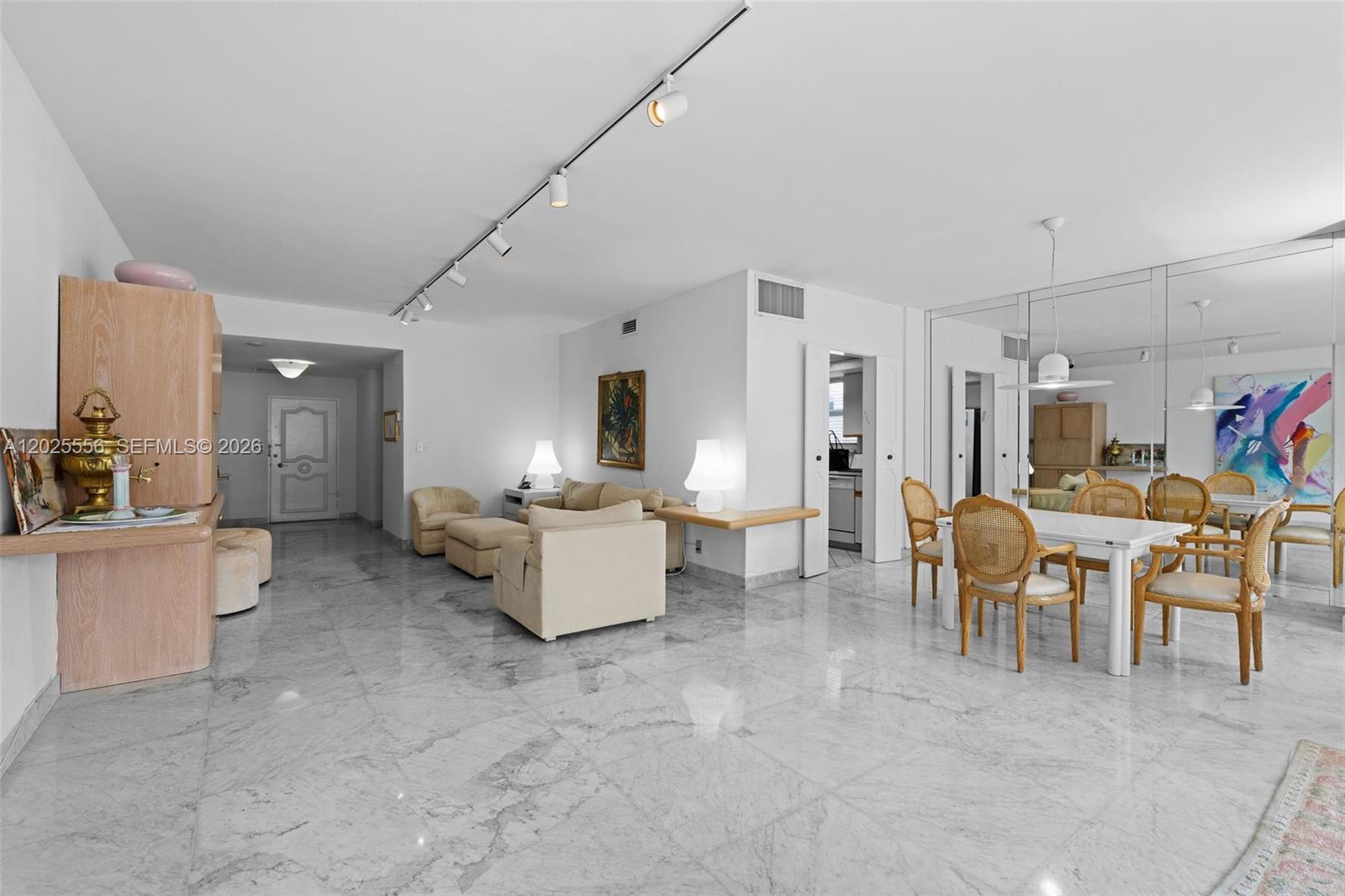 A living and dining area features white marble floors, track lighting, and mirrored walls — 4925 Collins Ave # 1A, Miami Beach FL 33140, MIAMI BEACH, FL
