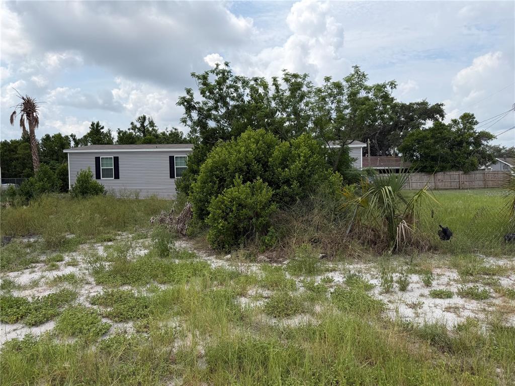 A vacant, grassy lot with sandy patches and a neighboring house in the background — 2438 EDWIN STREET NE, WINTER HAVEN, FL