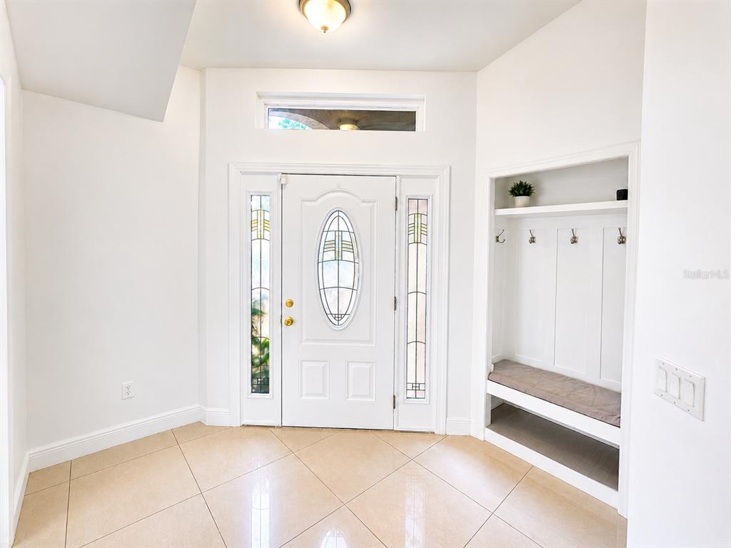 An entryway features a white front door with sidelights, tile flooring, and a built-in bench — 12786 MARIBOU CIRCLE, ORLANDO, FL