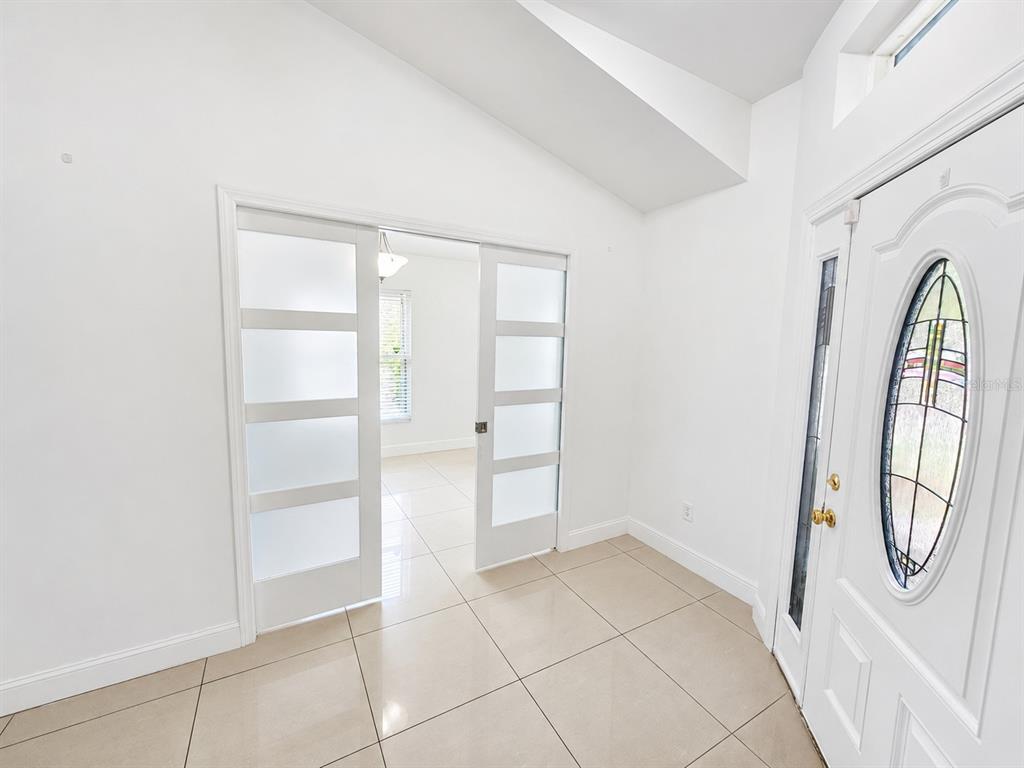 An entryway with light tile flooring, white walls, and sliding glass-paneled doors — 12786 MARIBOU CIRCLE, ORLANDO, FL