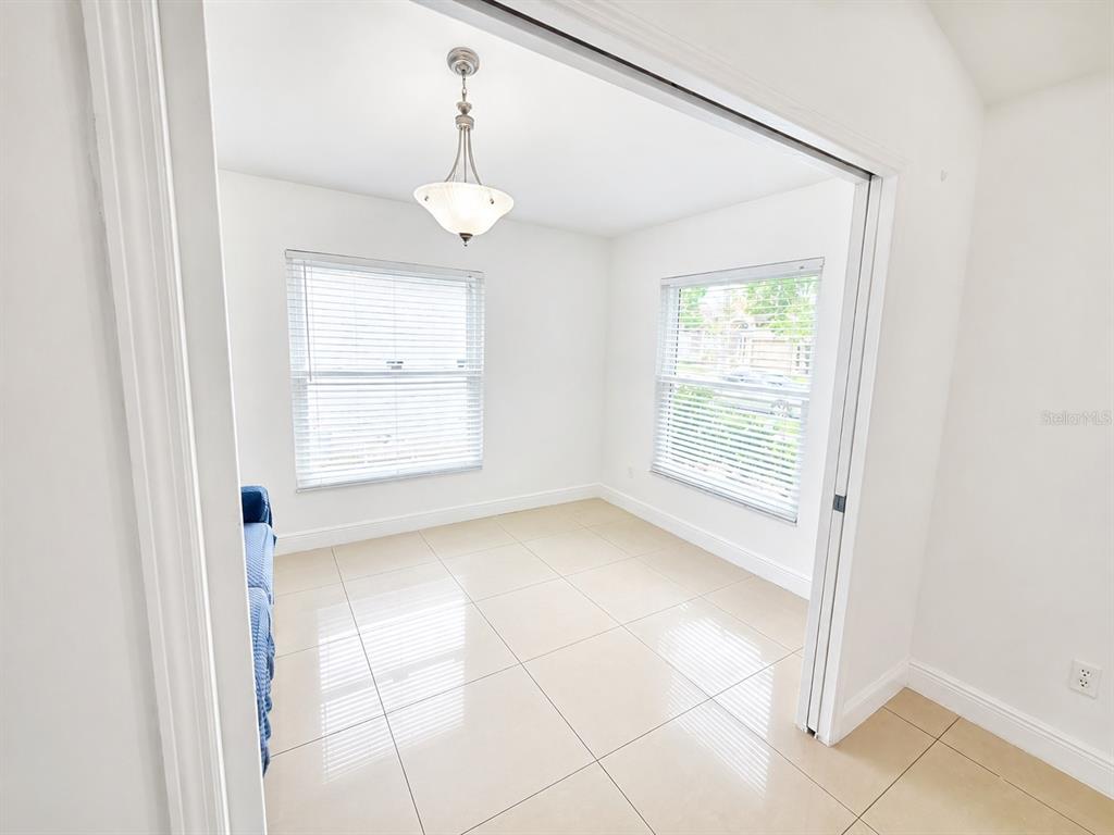 A bright room with white walls, tile flooring, two windows, and a hanging light fixture — 12786 MARIBOU CIRCLE, ORLANDO, FL