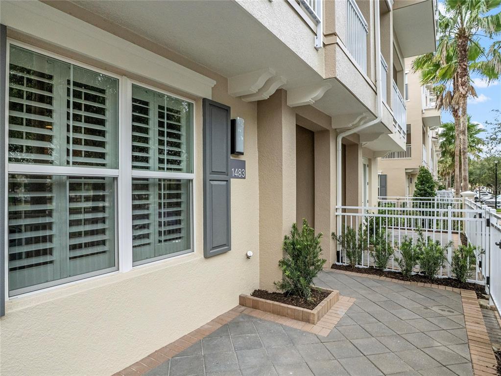 A paved walkway leads to the entrance of a beige townhouse with a shuttered window — 1483 LAKE GEORGE DRIVE, LAKE MARY, FL