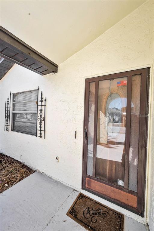 A view of a home's exterior entryway featuring a brown storm door and a window — 12813 KELLYWOOD CIRCLE, HUDSON, FL