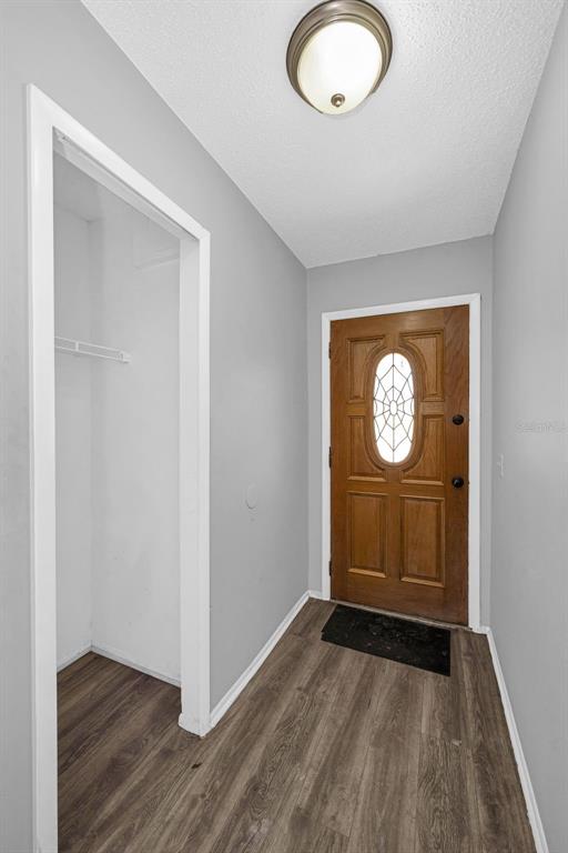 An entryway features wood-look flooring, a coat closet, and a wooden front door with glass — 12813 KELLYWOOD CIRCLE, HUDSON, FL