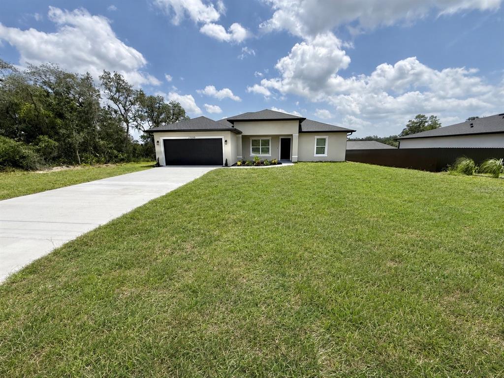 A single-story house with a black garage door and a concrete driveway sits on grass — 17229 SW 42ND TERRACE, OCALA, FL
