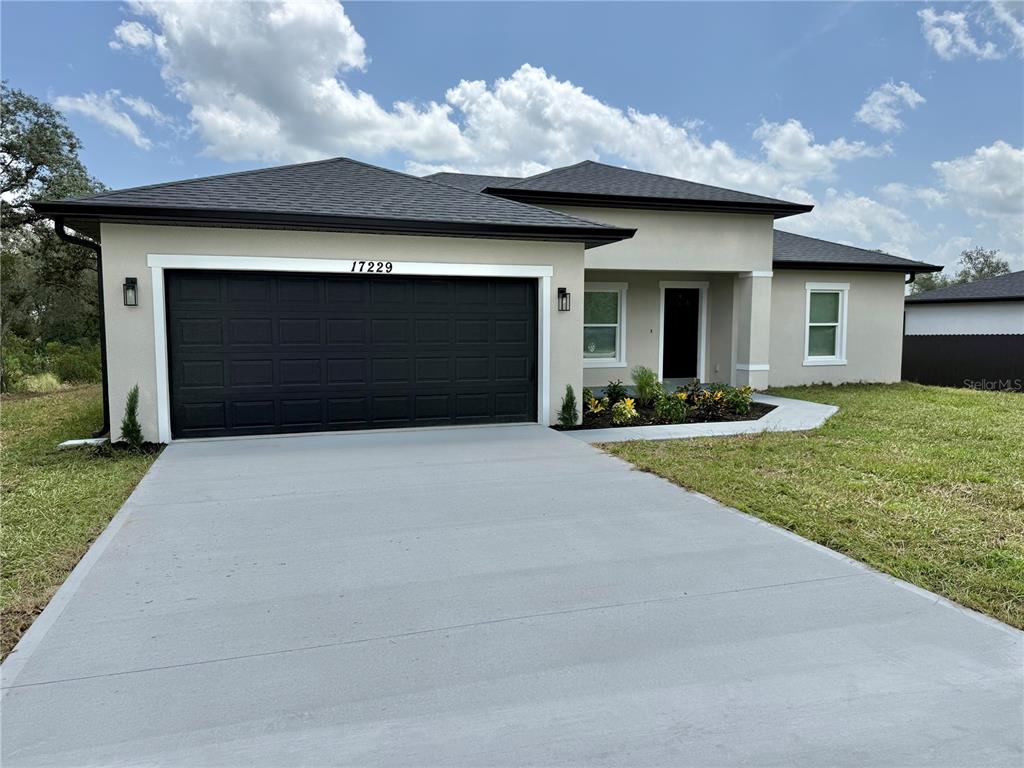 A single-story house with a black garage door, stucco exterior, and a concrete driveway — 17229 SW 42ND TERRACE, OCALA, FL