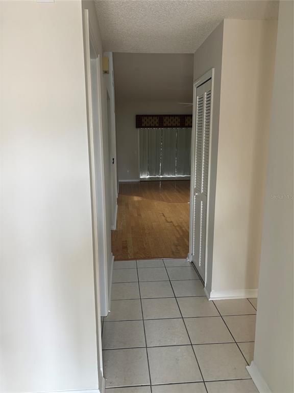 A tiled hallway leads to a living area with hardwood floors and a sliding glass door — 2449 GRAND TETON CIRCLE UNIT 2449, WINTER PARK, FL