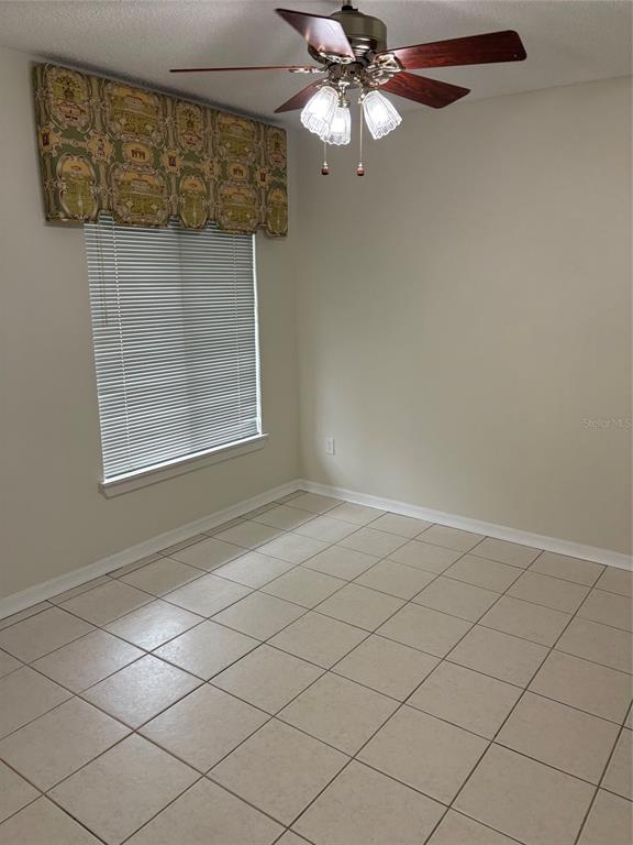 An empty room with beige tile flooring, a ceiling fan, and a window with blinds — 2449 GRAND TETON CIRCLE UNIT 2449, WINTER PARK, FL