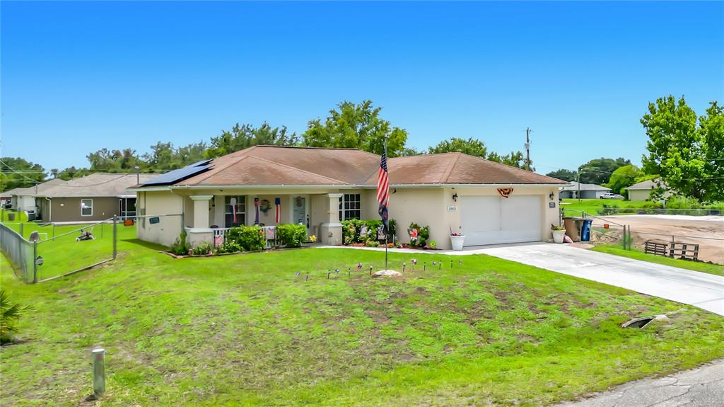 A single-story house with a tan exterior, a two-car garage, and an American flag — 2903 38TH STREET SW, LEHIGH ACRES, FL