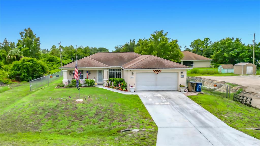A single-story house with a two-car garage, a front porch, and an American flag — 2903 38TH STREET SW, LEHIGH ACRES, FL