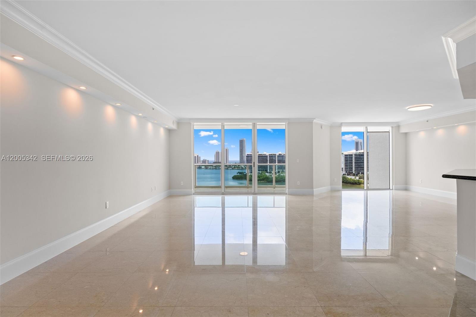 An empty living room features polished tile floors, recessed lighting, and floor-to-ceiling windows overlooking water — 3301 NE 183rd St # 1604, Aventura FL 33160, AVENTURA, FL