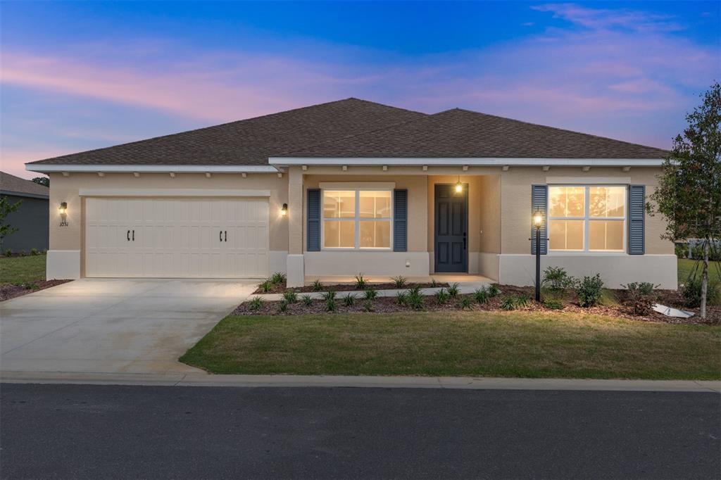 A single-story house with a beige stucco exterior, a two-car garage, and a front porch — 10313 SW 106TH COURT, OCALA, FL