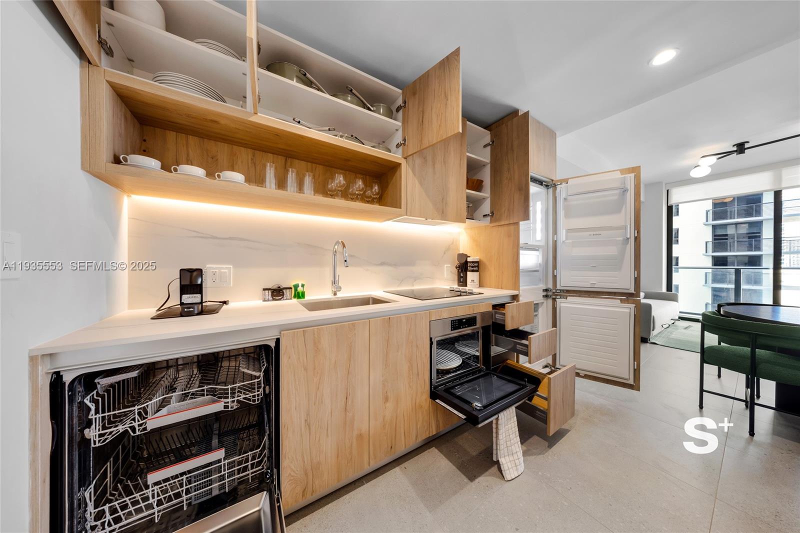 A modern kitchen features light wood cabinetry, white countertops, integrated appliances, and an open layout — 11 NE 6TH ST # 1910, Miami FL 33132, MIAMI, FL