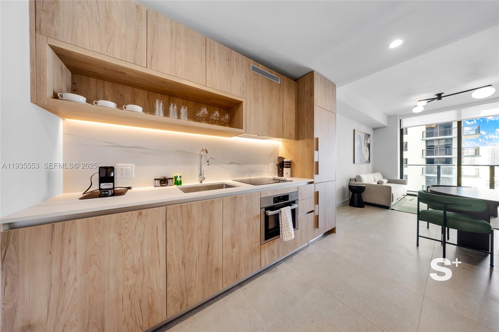 A modern kitchen features light wood cabinetry, a marble backsplash, and an adjacent dining area — 11 NE 6TH ST # 1910, Miami FL 33132, MIAMI, FL