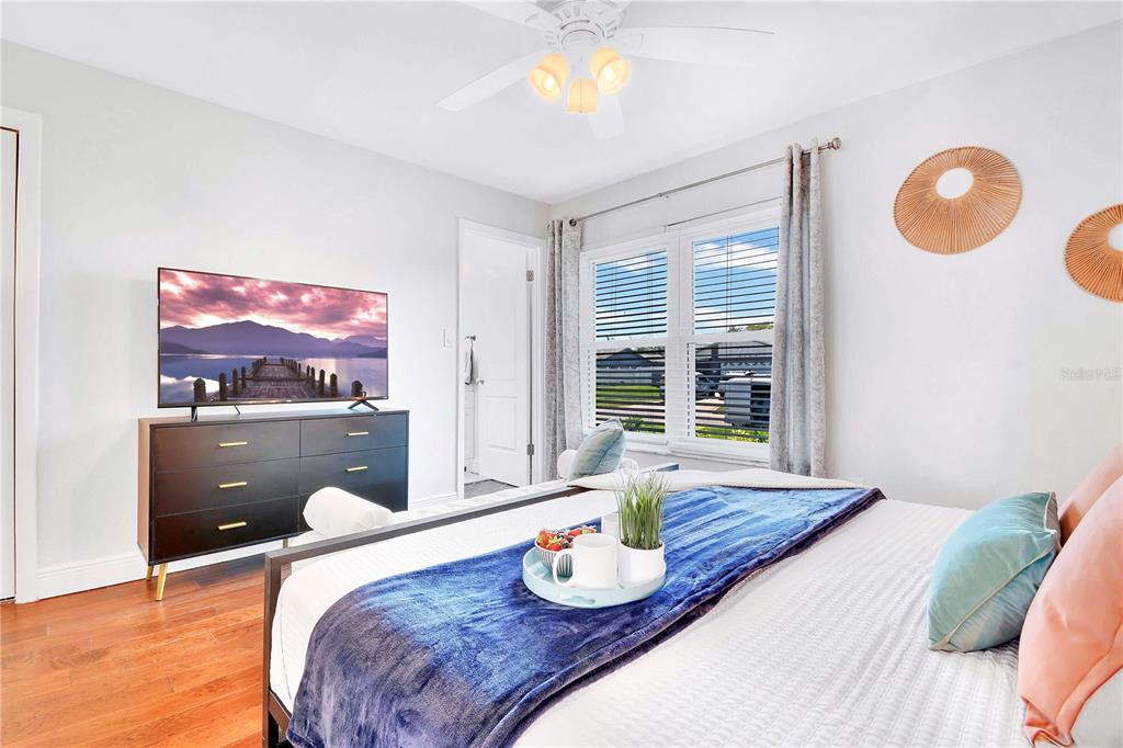 A bedroom features a bed with a blue throw, a television on a dresser, and windows — 5730 IMPERIAL KEY, TAMPA, FL