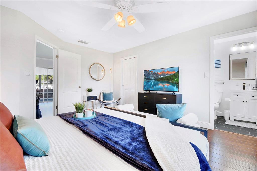 A bedroom features a bed with blue bedding, a television on a dresser, and an ensuite — 5730 IMPERIAL KEY, TAMPA, FL