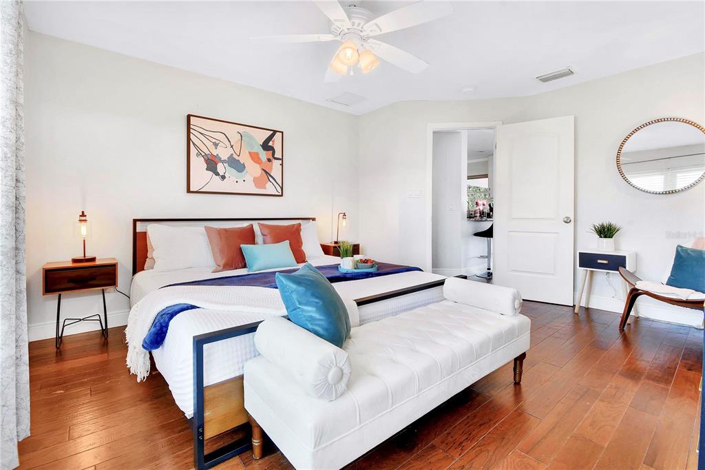 A bedroom features a bed with blue accents, a white bench, and hardwood flooring — 5730 IMPERIAL KEY, TAMPA, FL
