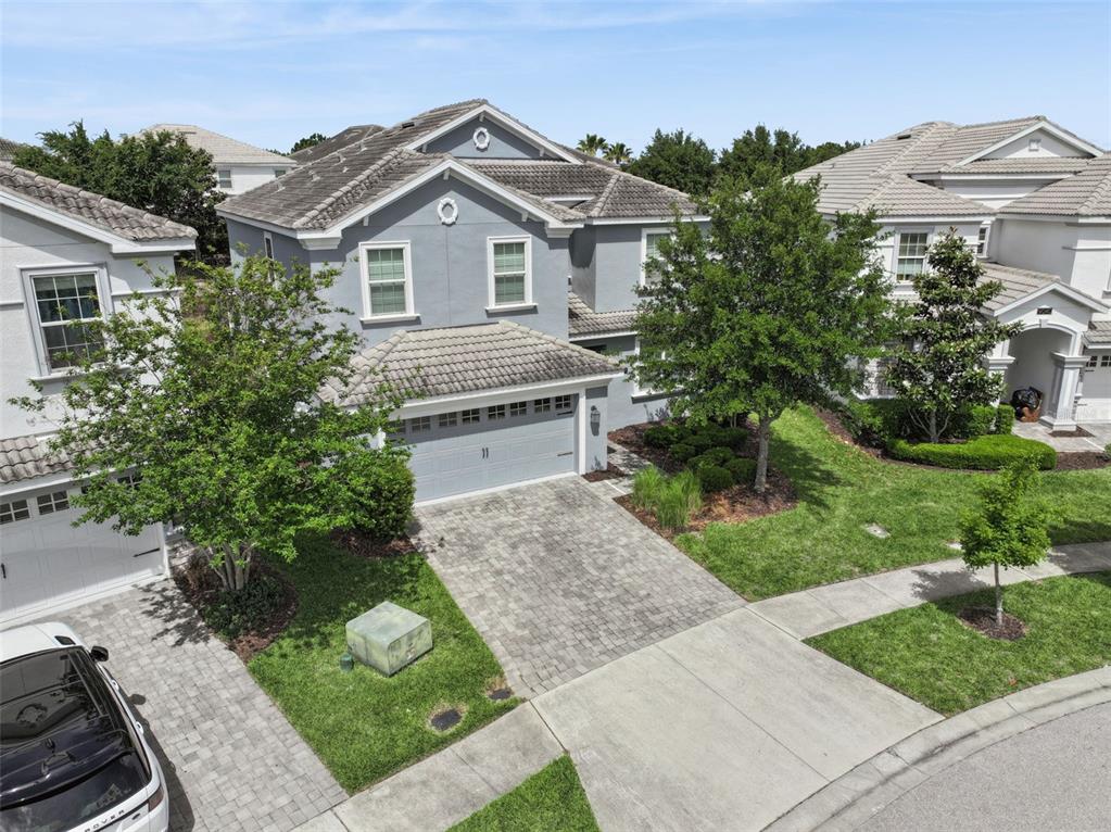 An aerial view shows a two-story gray house with a tiled roof and paved driveway — 9038 STINGER DRIVE, DAVENPORT, FL