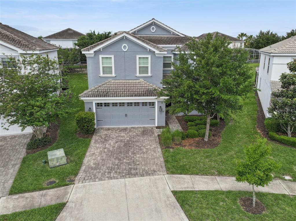 A two-story gray house with a tiled roof, a two-car garage, and a paved driveway — 9038 STINGER DRIVE, DAVENPORT, FL