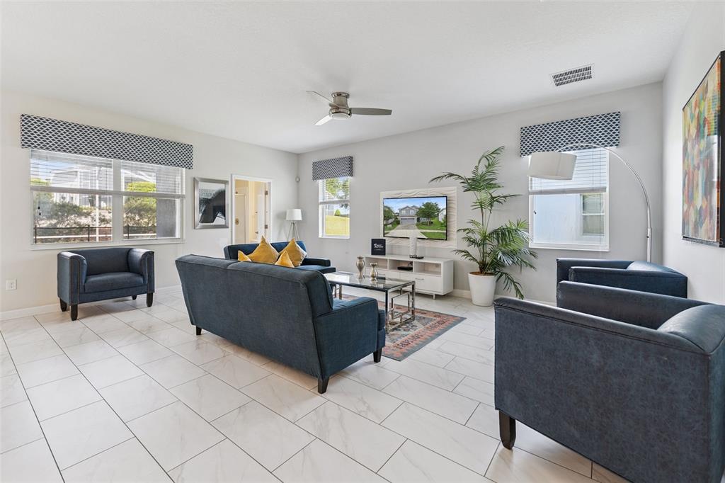 A living room features blue furniture, a television, a ceiling fan, and white tiled floors — 9038 STINGER DRIVE, DAVENPORT, FL