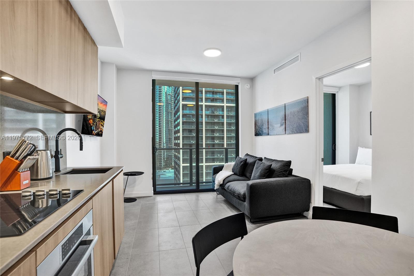 A modern apartment features an open kitchen, a living area with a sofa, and a bedroom — 121 NE 5th St # 2411, Miami FL 33132, MIAMI, FL