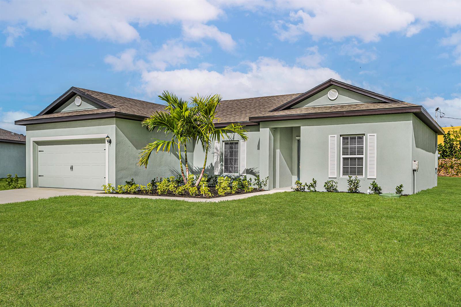 A single-story house with a light green stucco exterior, a two-car garage, and a palm tree — 9375 103rd Avenue, Vero Beach FL 32967, VERO BEACH, FL