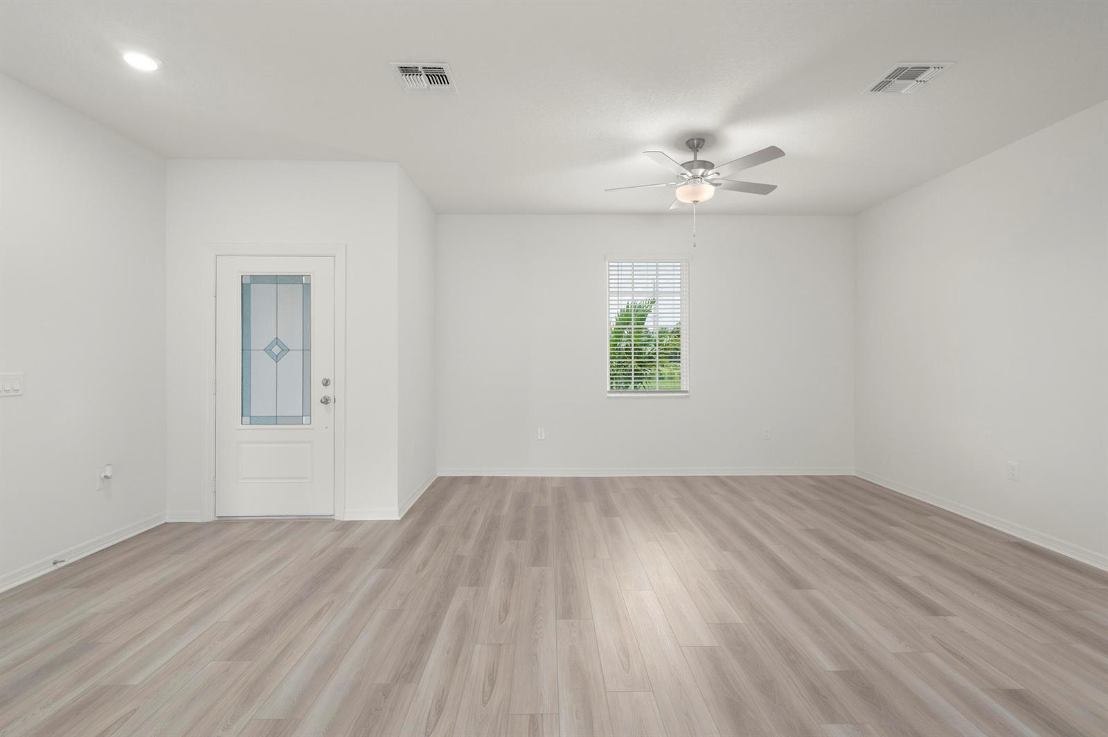 An empty room with white walls, light wood-look flooring, a ceiling fan, and a door — 9375 103rd Avenue, Vero Beach FL 32967, VERO BEACH, FL