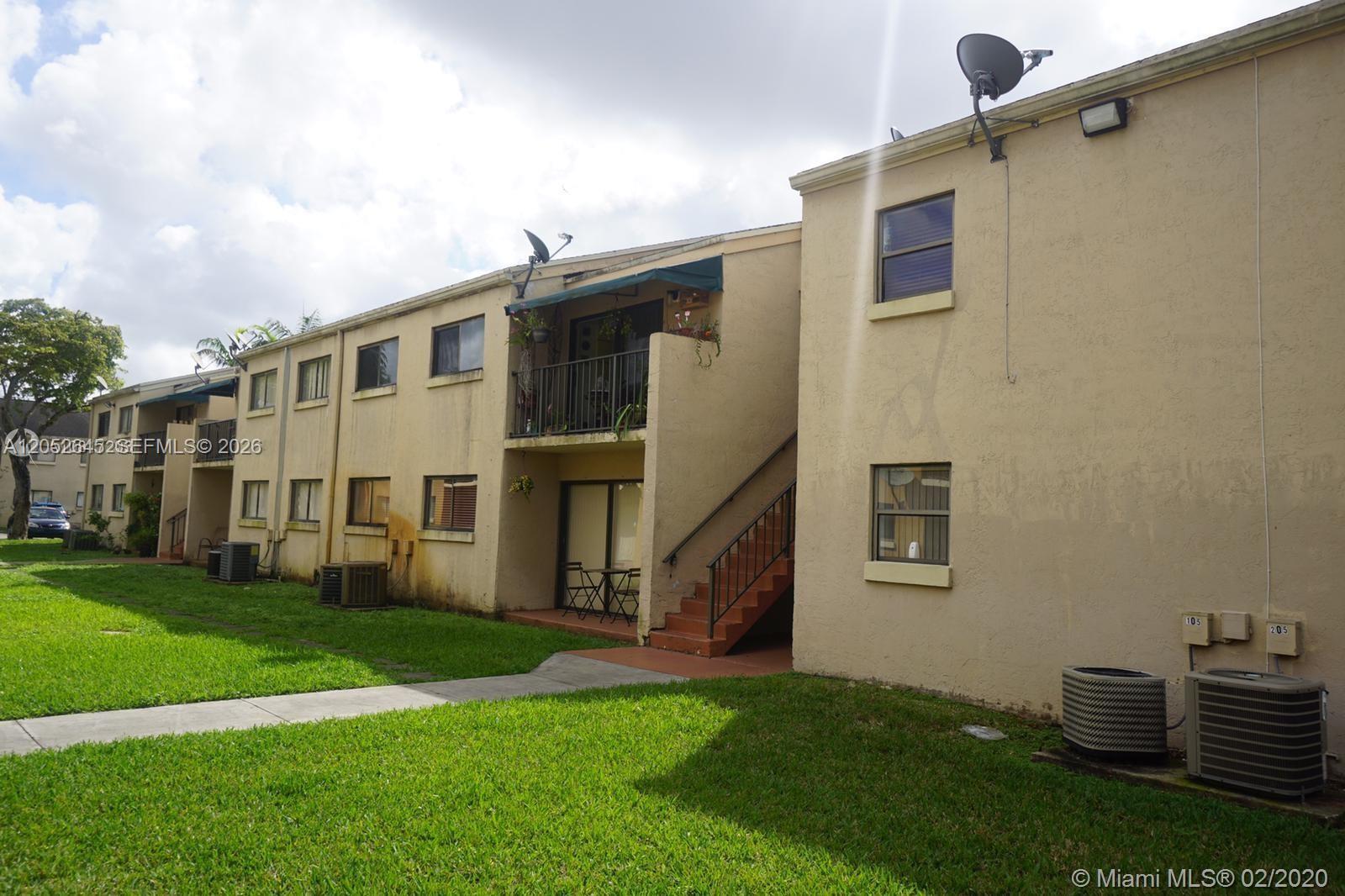 A two-story apartment building exterior features tan stucco walls, a metal staircase, and green lawns — 7403 SW 152nd Ave # 2, Miami FL 33193, MIAMI, FL