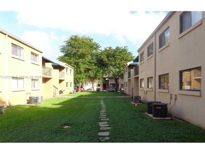 A grassy courtyard sits between two multi-story apartment buildings with a stone path in between — 7403 SW 152nd Ave # 2, Miami FL 33193, MIAMI, FL