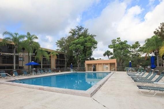 A rectangular swimming pool is surrounded by lounge chairs and palm trees near a building — 7403 SW 152nd Ave # 2, Miami FL 33193, MIAMI, FL
