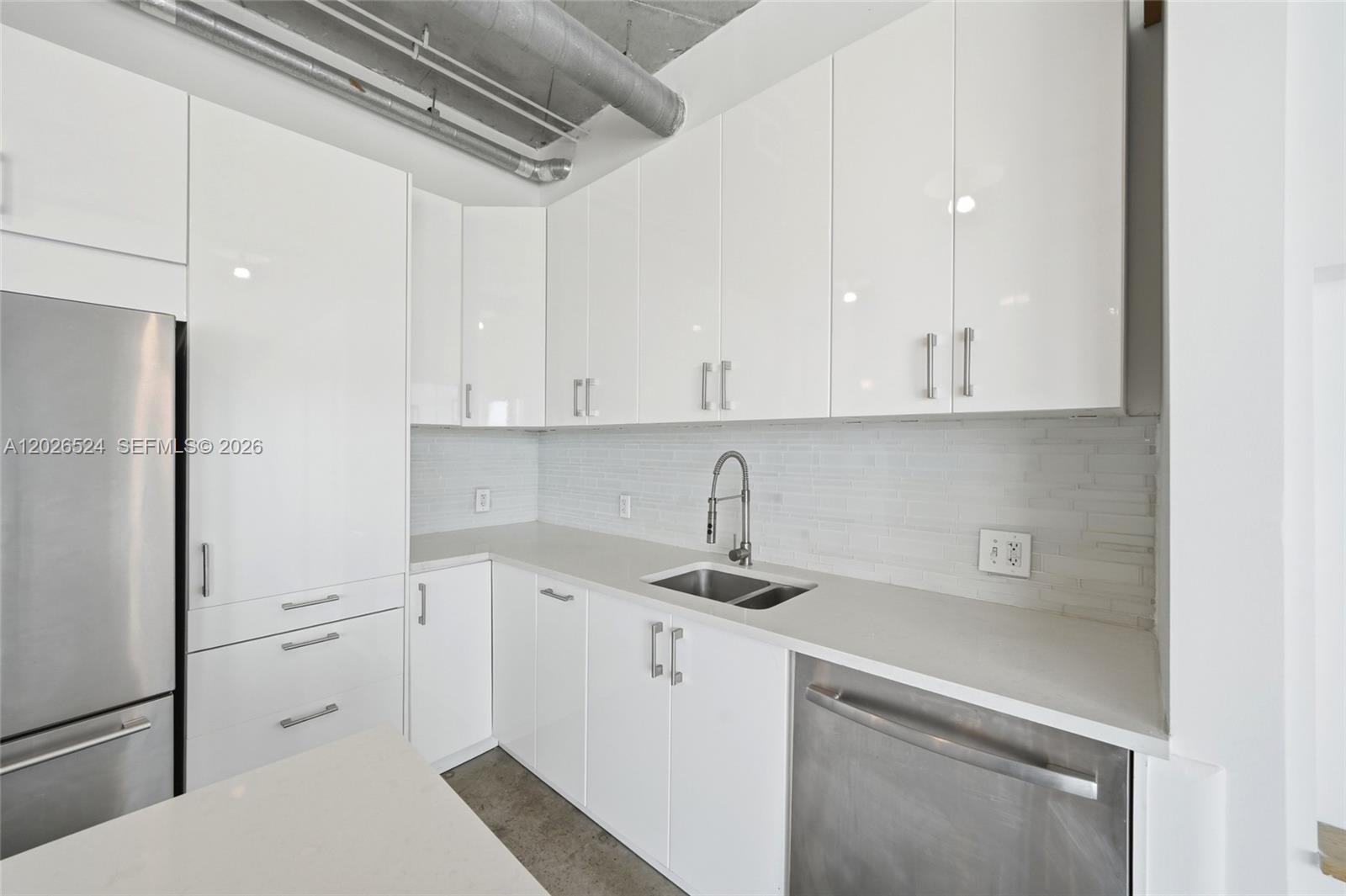 A modern kitchen features white cabinets, stainless steel appliances, and an exposed industrial ceiling — 10 SW South River Dr # 804, Miami FL 33130, MIAMI, FL