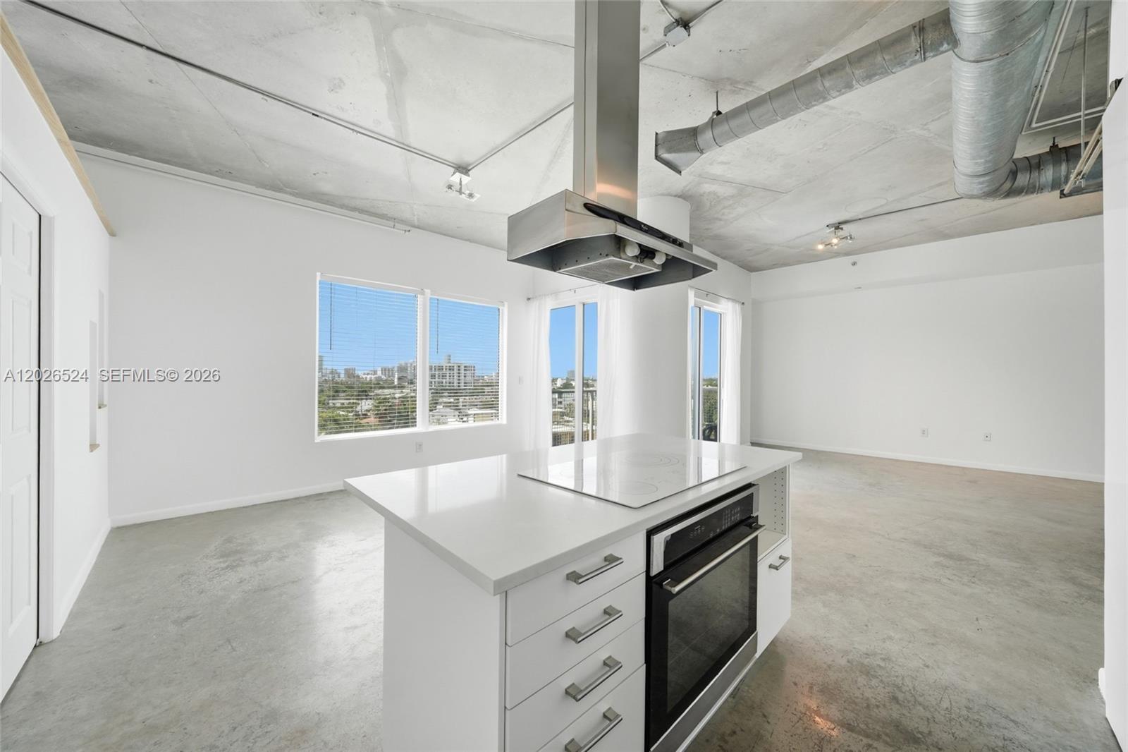 A kitchen island with a built-in oven sits in an open-concept room with concrete ceilings — 10 SW South River Dr # 804, Miami FL 33130, MIAMI, FL